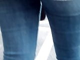 Young sexy girl in blue tight jean waiting at a bus stop 1